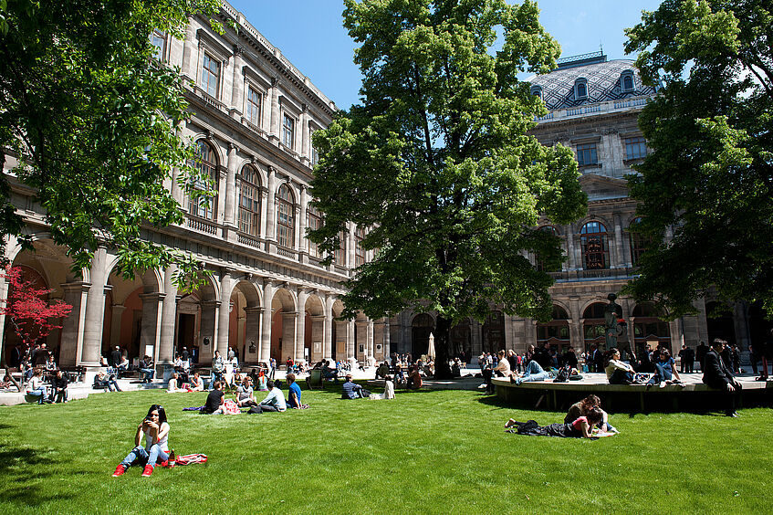 Students sitting and studying in the courtyard of the main building in summer.